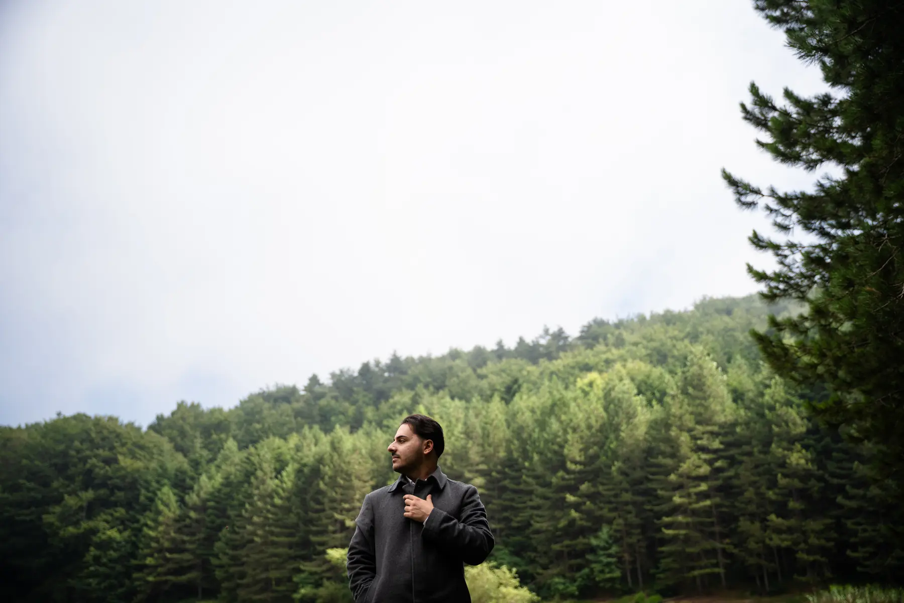 Luigi Gordano standing in a coat in front of a pine forest